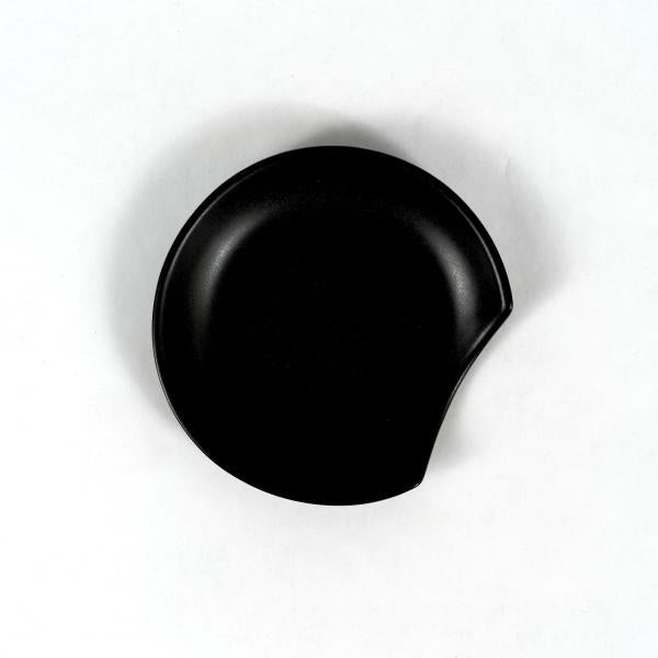 Black stoneware notched round spoon rest on a white background.