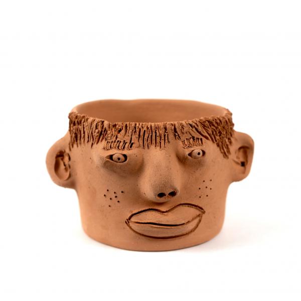 Clay plant pot featuring a quirky face with ears. 