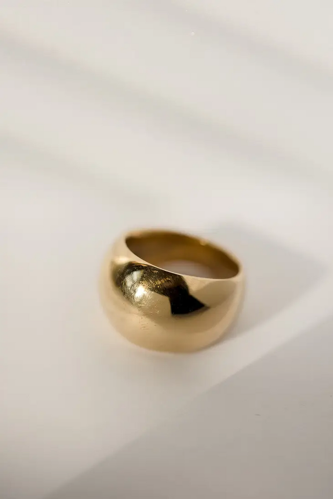 A flat wide domed brass ring on a white background.