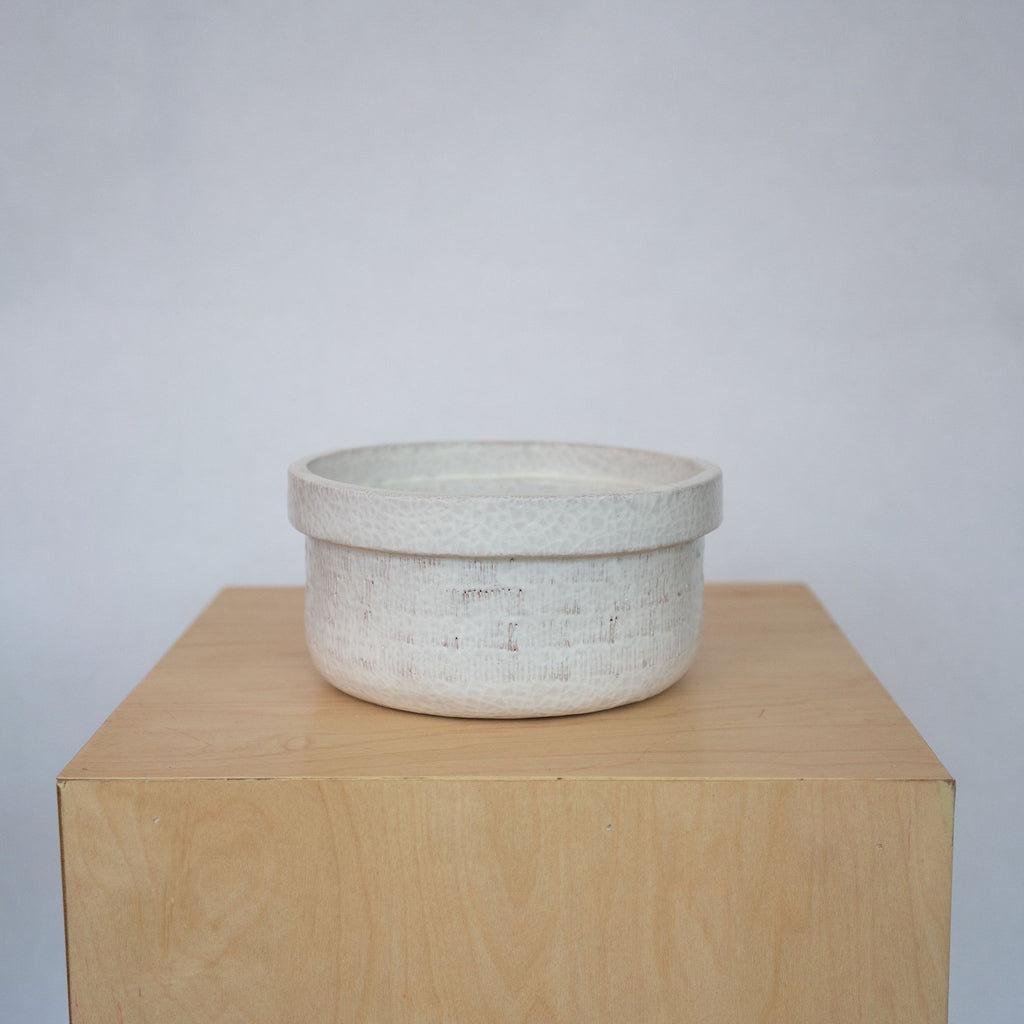 Small white ceramic bowls on a wood platform in front of a white background.