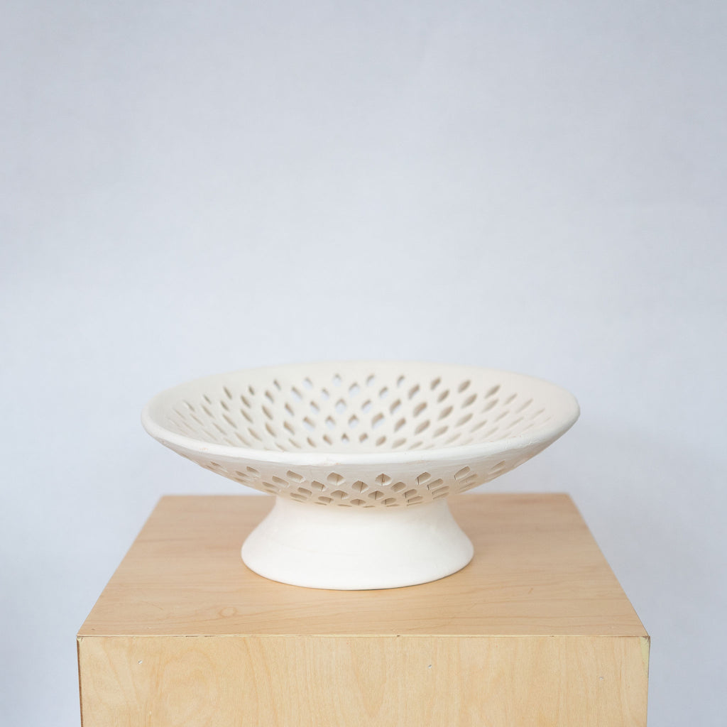 Cream ceramic fruit bowl with lacework design.