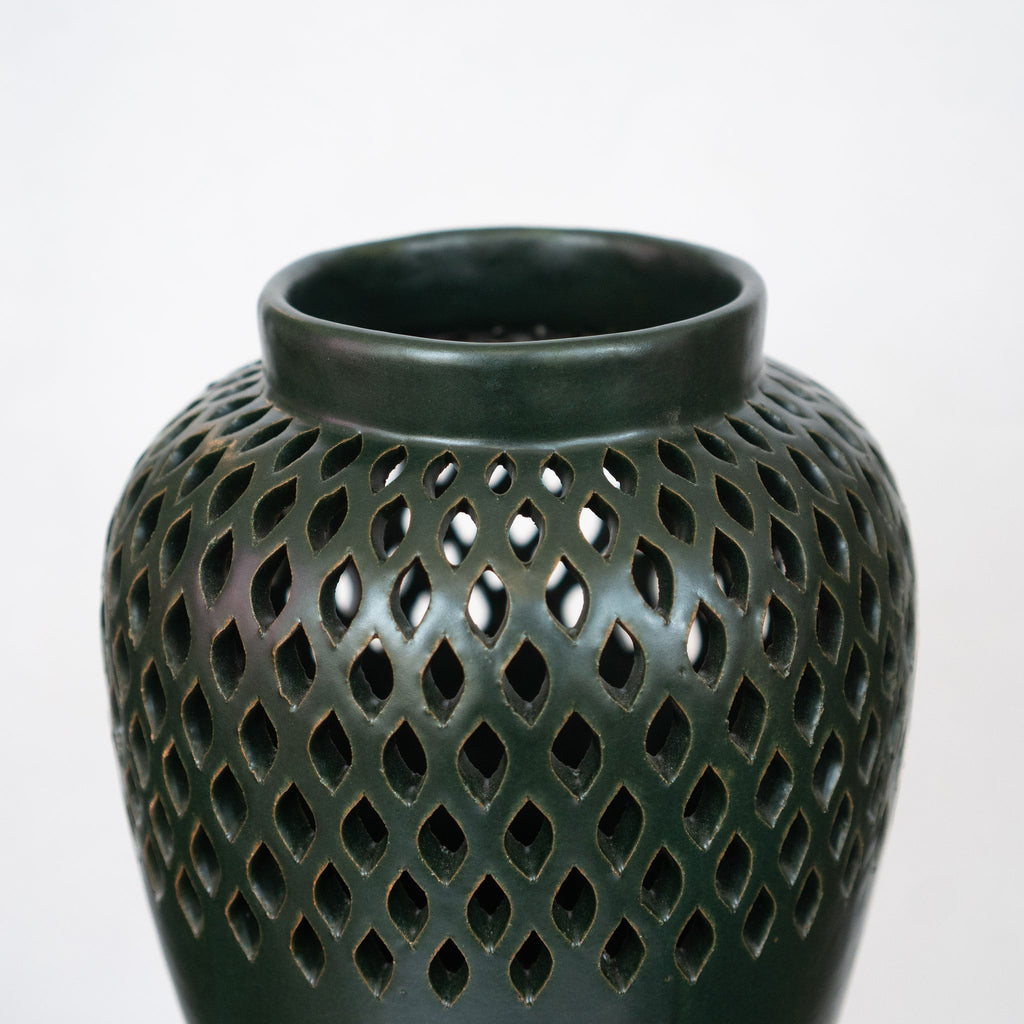 Detail shot of the lacework detail of dark green ceramic vase.
