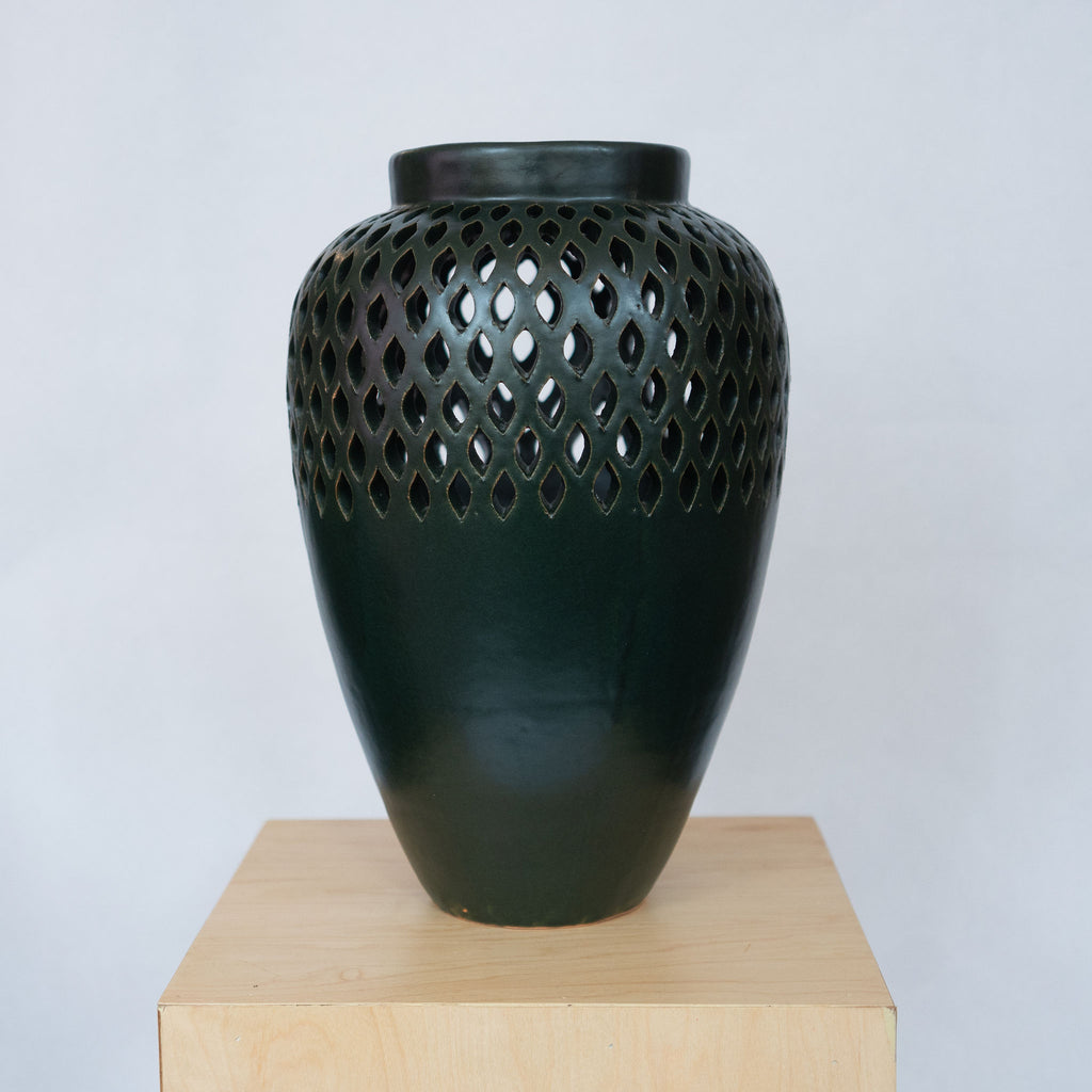 Large dark green ceramic vase with a lacework top. 