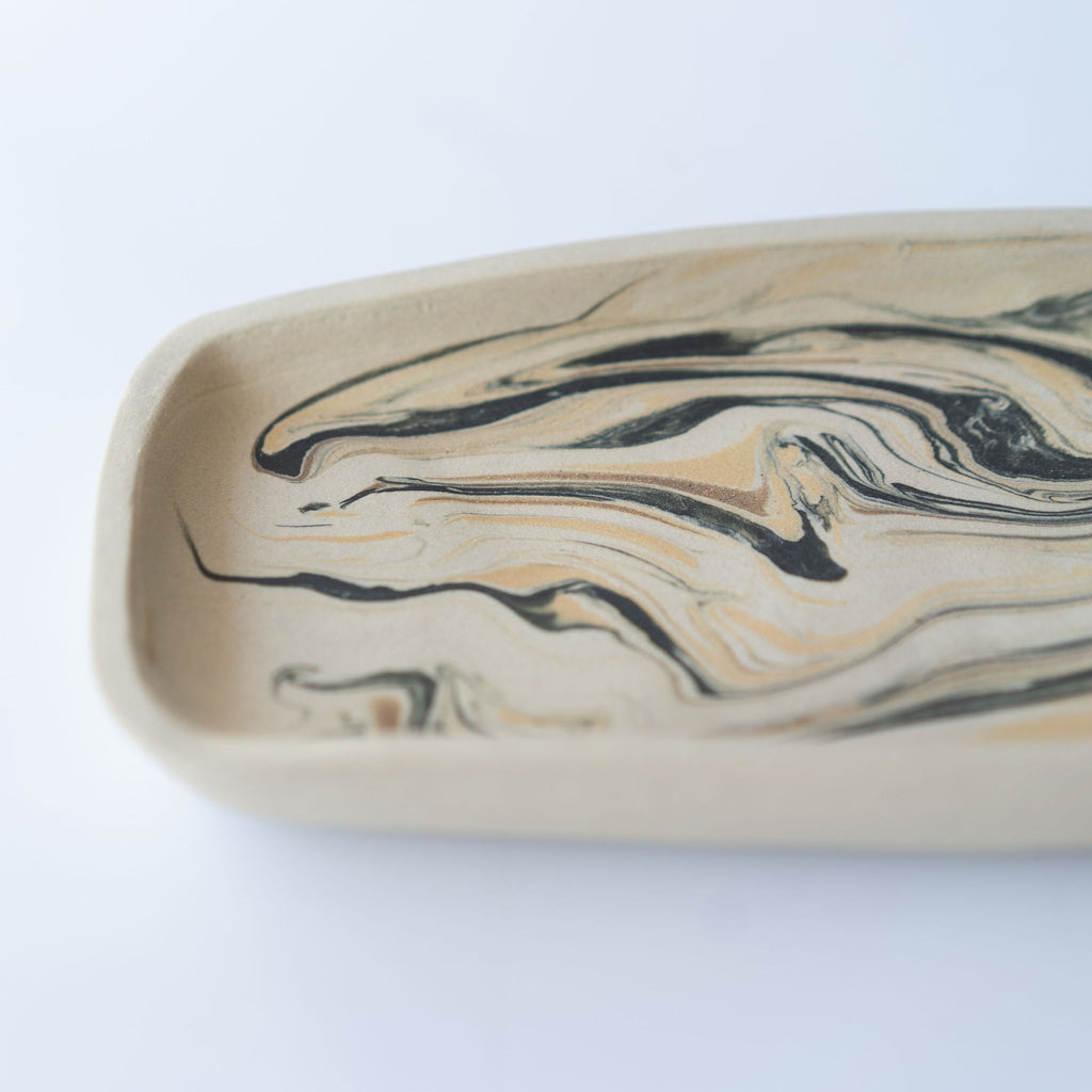 Close up of black and tan marbled rectangular plate with a slightly raised edge.