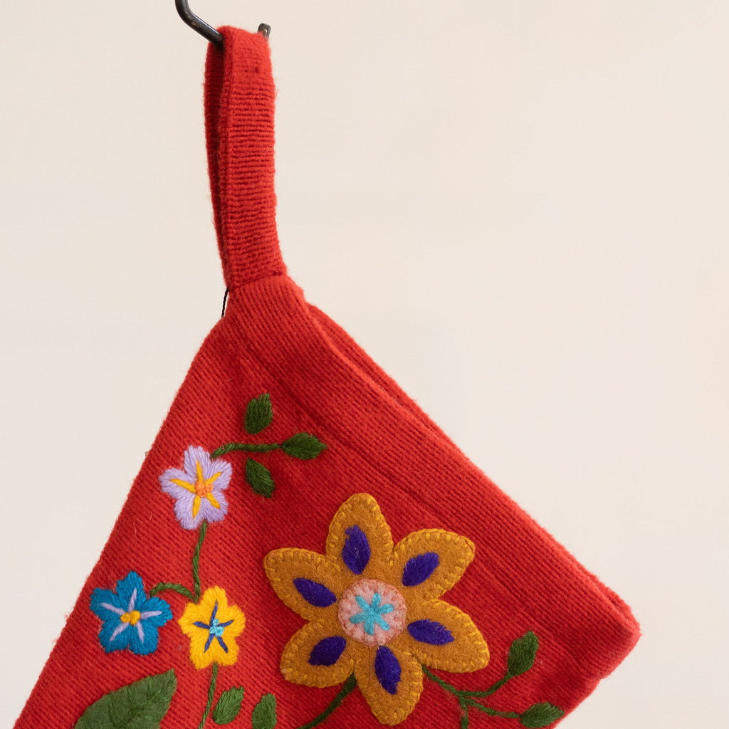 Detail of red wool stocking with a bright and colorful embroidered Peruvian floral design.