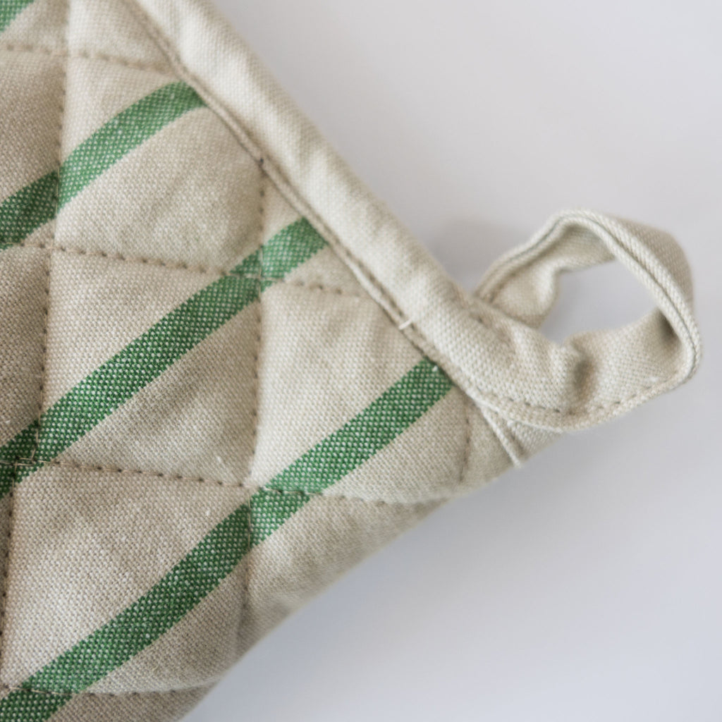 Close up of hanging loop of a Cream oven glove with green stripes on a white background.