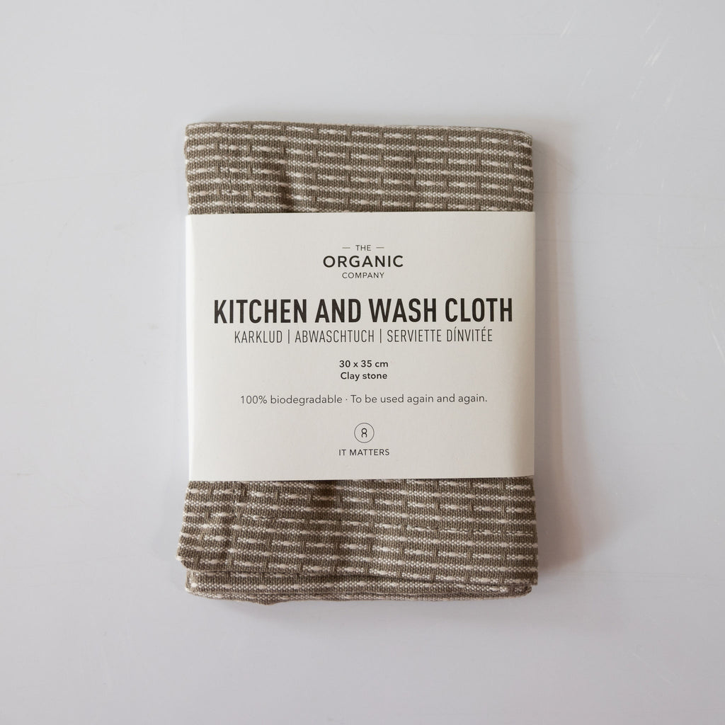 Organic cotton pique woven kitchen and washcloth folded with a label around it. Tan and cream subtle striping.