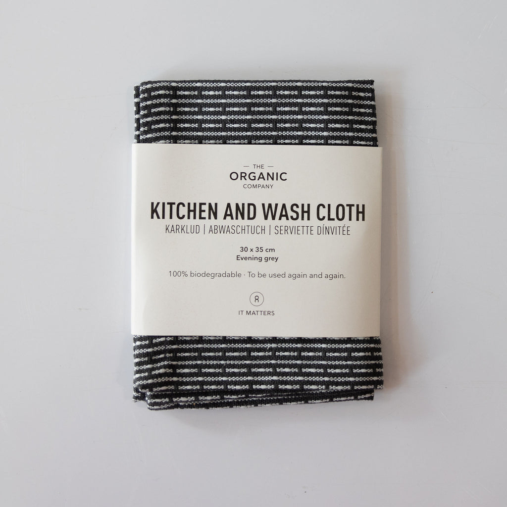 Organic cotton pique woven kitchen and washcloth folded with a label around it. Dark gray and cream subtle striping.