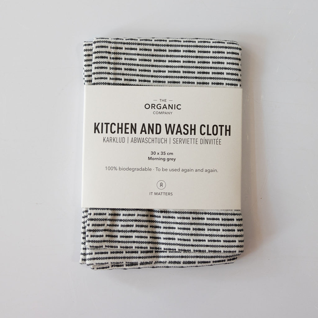 Organic cotton pique woven kitchen and washcloth folded with a label around it. Light gray and cream subtle striping.
