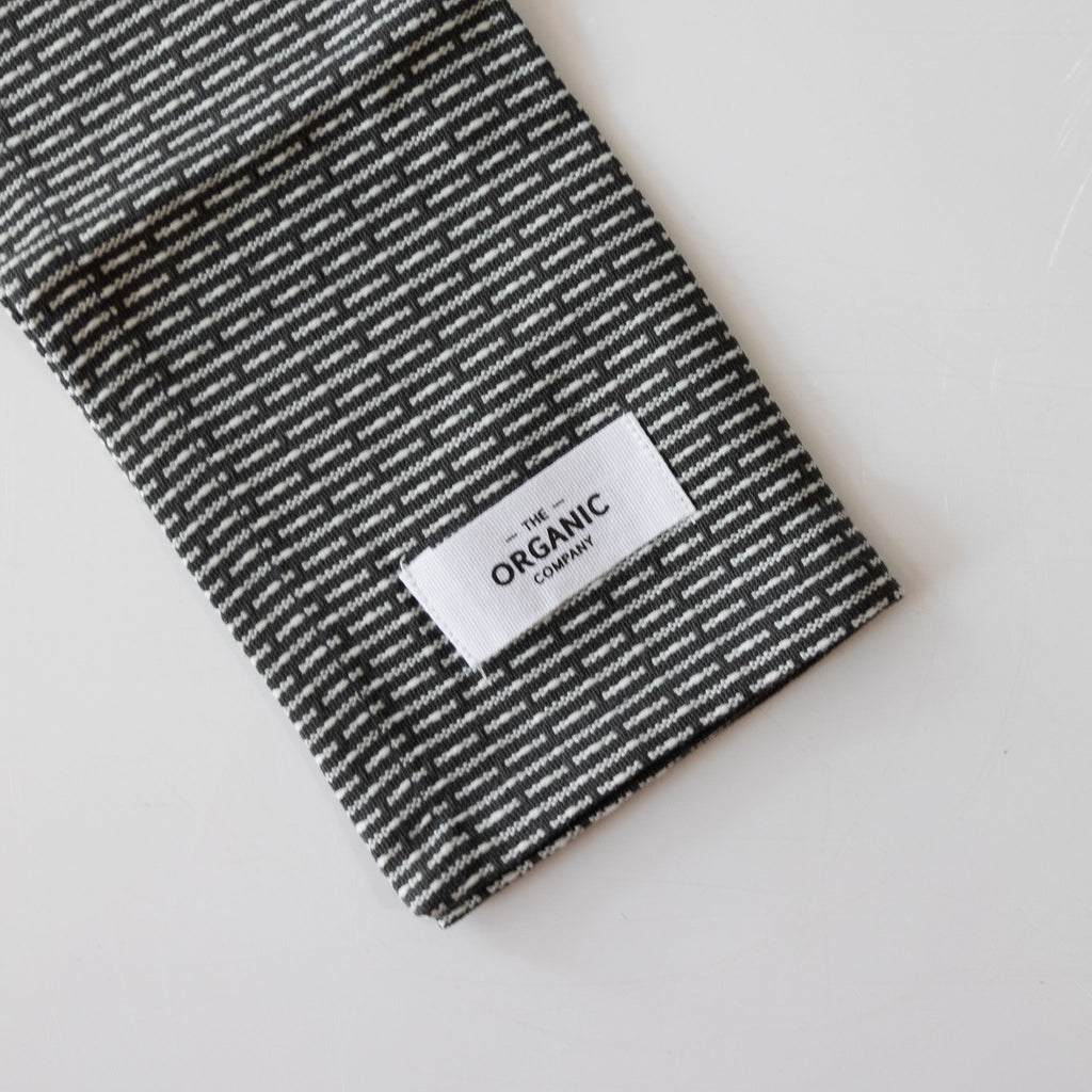 Organic cotton pique woven kitchen and washcloth folded on a white background. Dark gray and cream subtle striping.