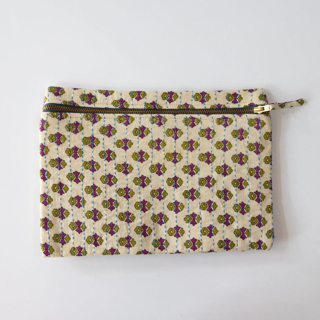 A zipper pouch clutch that is handmade and embroidered with the traditional Kantha stitch over recycled sari fabric in cream and olive green and orchid purple floral pattern. White background.