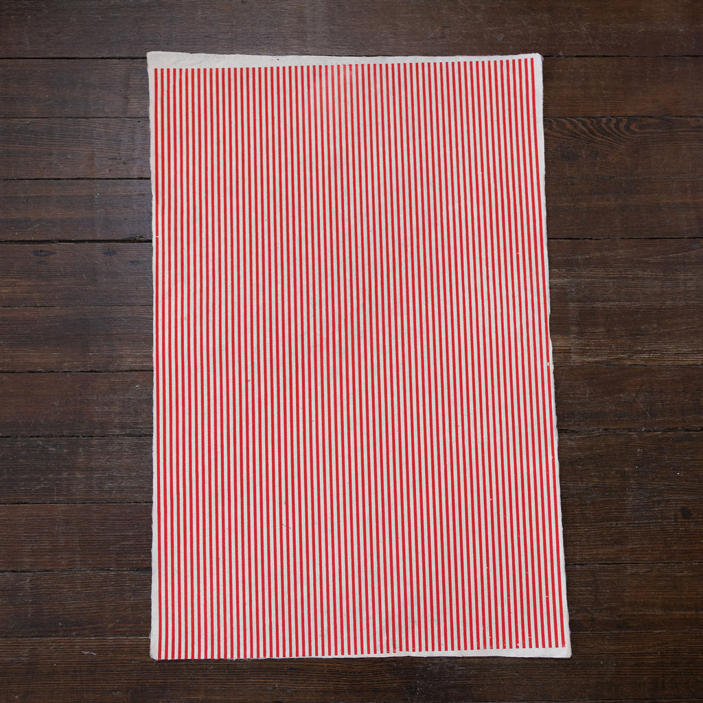 Handmade and printed paper gift wrap. Pattern is repeat thin red stripes on white background.