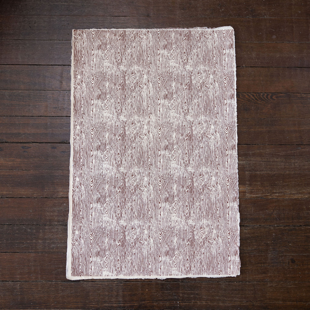 Handmade and printed paper gift wrap. Pattern is repeat brown wood grain on white background.