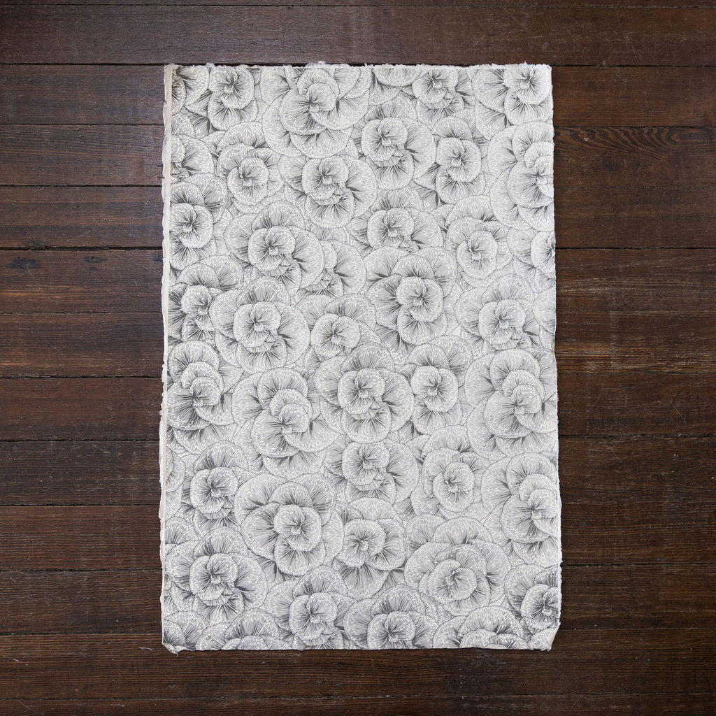 Handmade and printed paper gift wrap. Pattern is repeat gray blossoms on cream background.