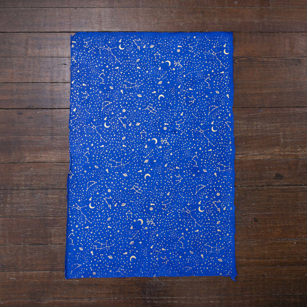Handmade and printed paper gift wrap. Pattern is repeat Gold constellations on bright blue background.