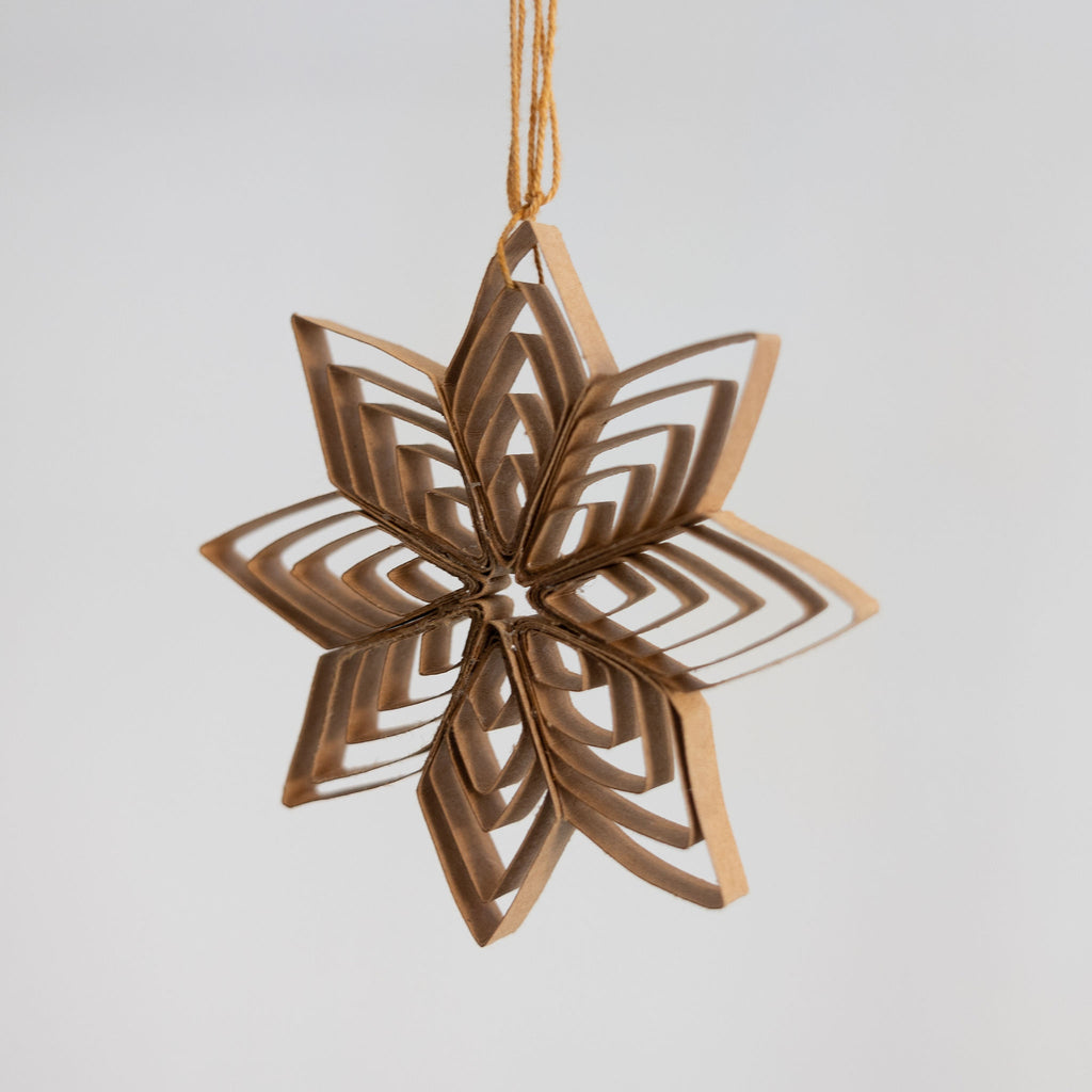 8 point radiating quilled paper start holiday decoration in Kraft paper color hanging in front of a light gray background.