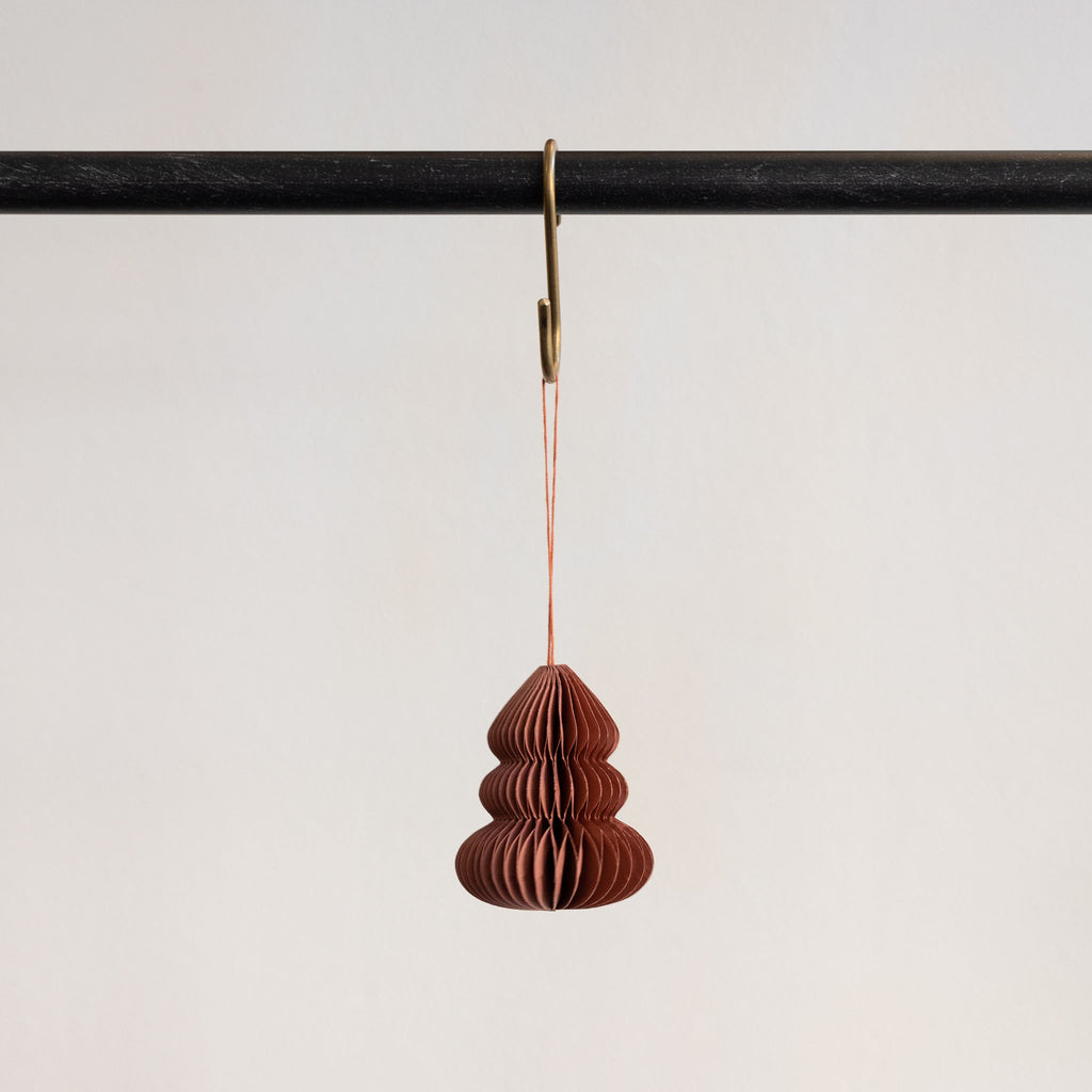 Recycled paper accordion tree ornament in Mauve hanging from a brass hook on a black bar in front of a white background.