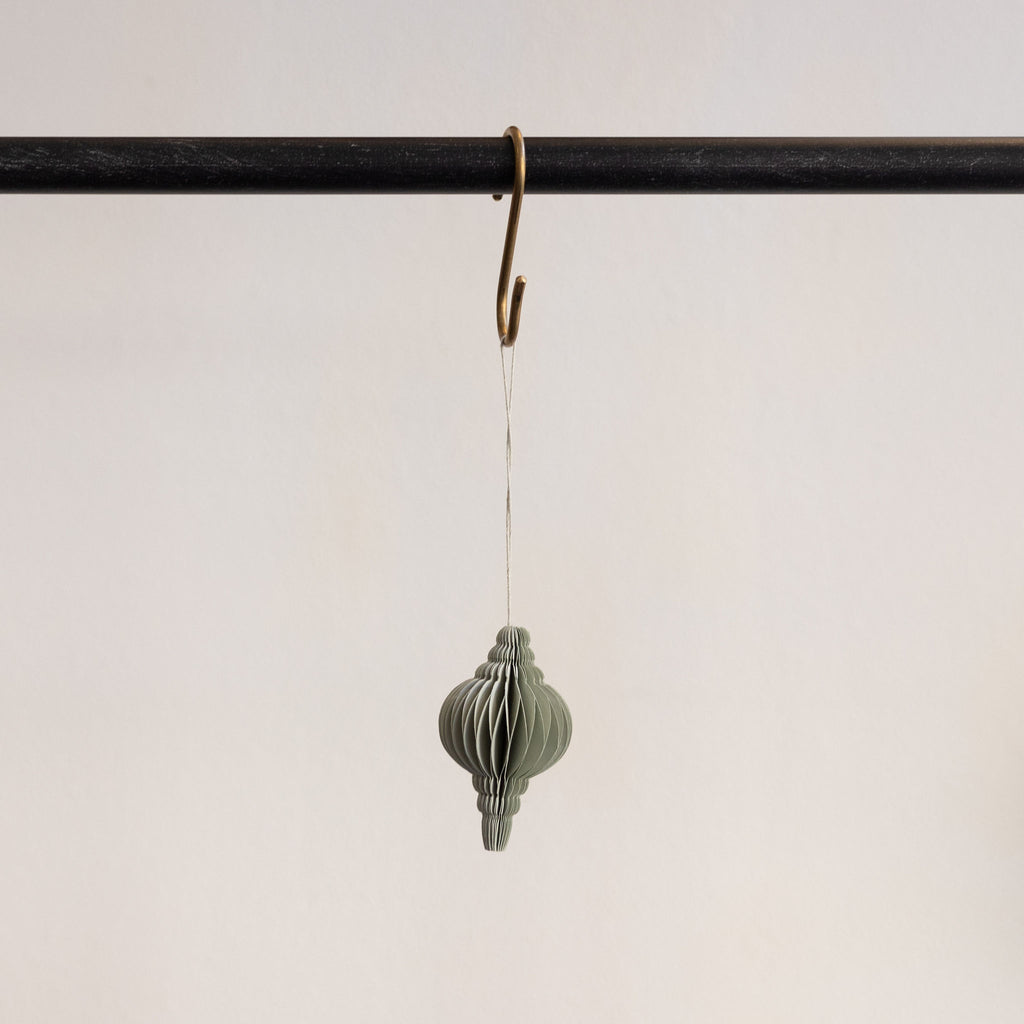 Recycled paper accordion tree ornament in Seafoam Green hanging from a brass hook on a black bar in front of a white background.