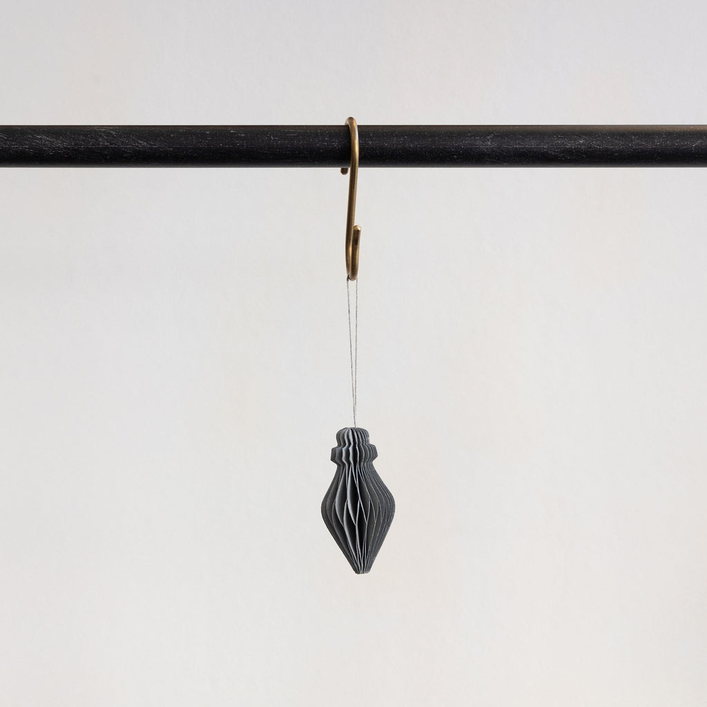 Recycled paper accordion tree ornament in Cool Gray hanging from a brass hook on a black bar in front of a white background.
