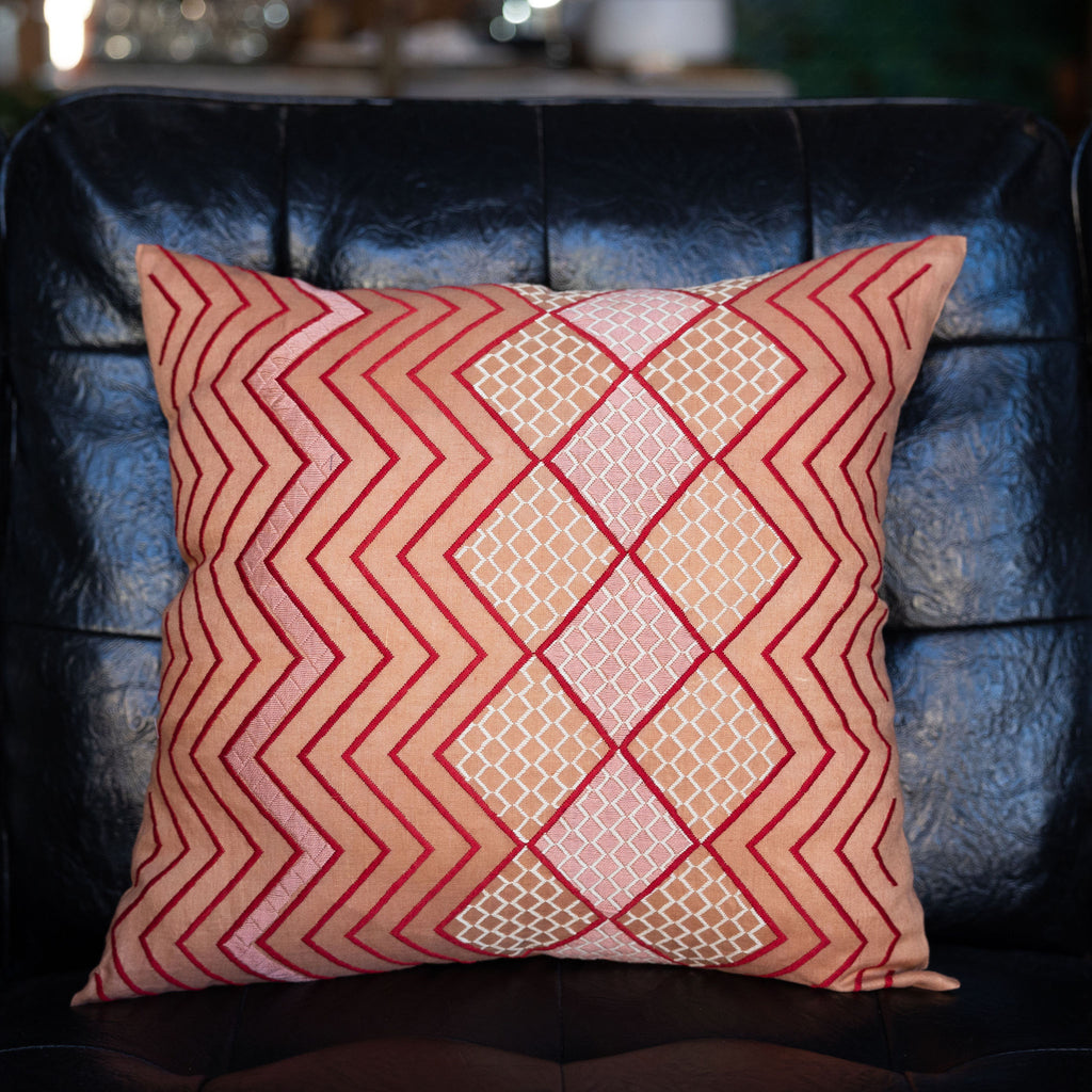 Embroidered tangerine square pillow featuring red zig zag and blush pink and cream diamond embroidery.