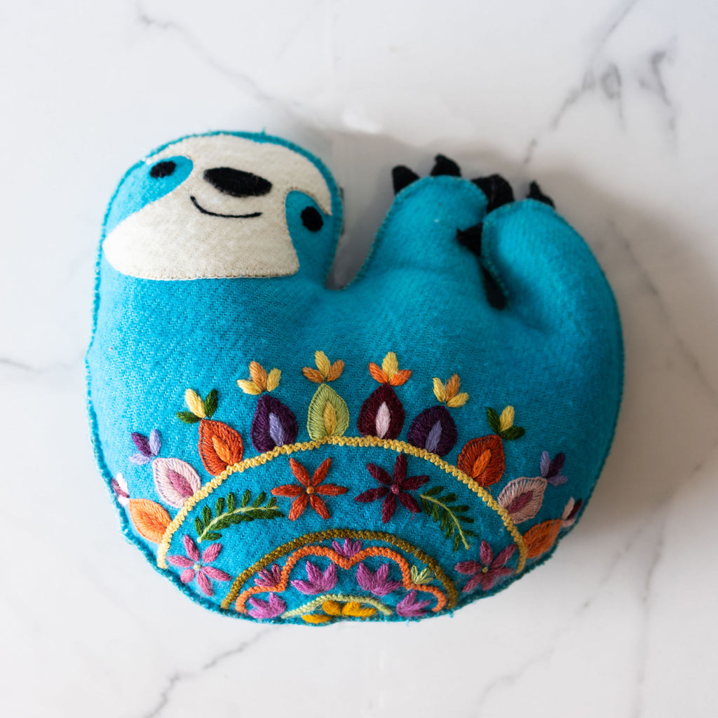 Very cute blue sloth pillow with bold and colorful Peruvian floral embroidery.