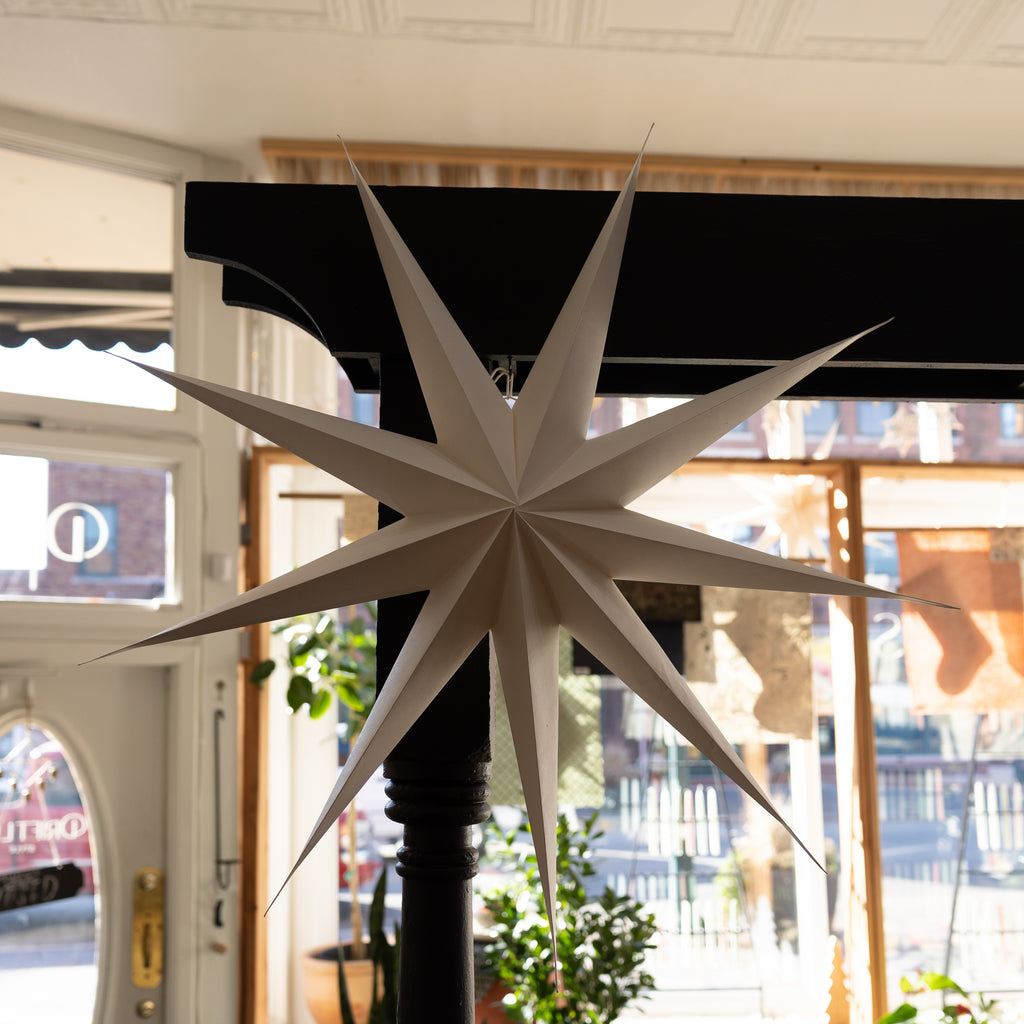 3D 9-Point paper star that stores flat. In a shop with a holiday background in front of big windows.