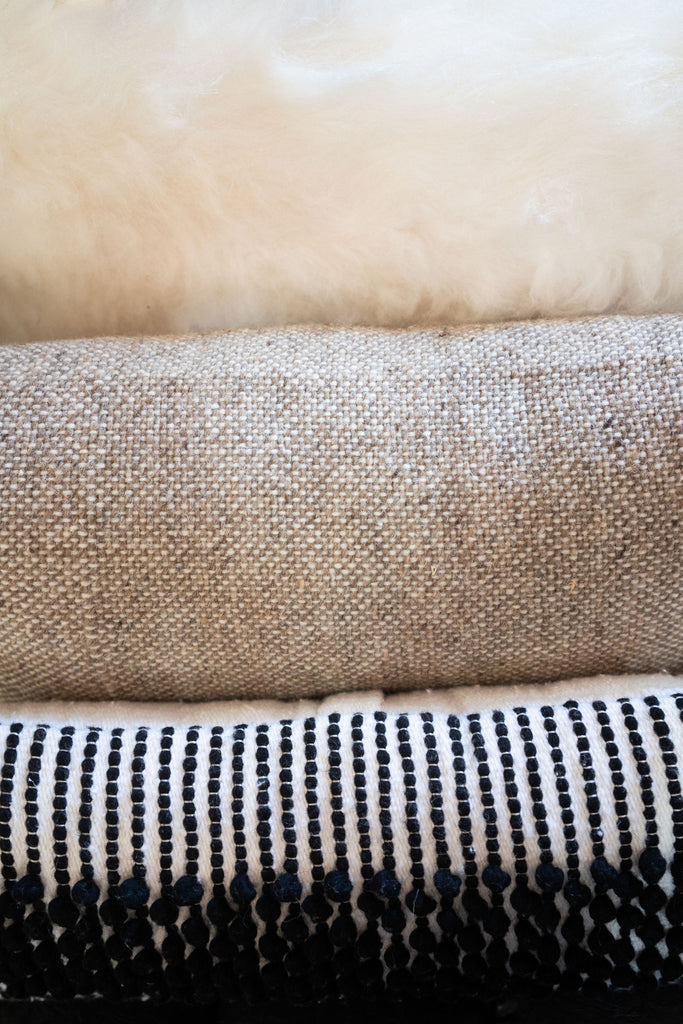 Detail shot of textural wool pillows. Cream, tan, and black.