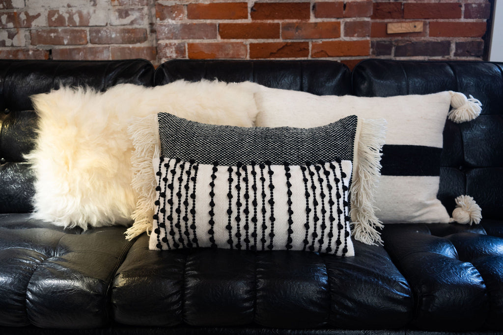 Group of four wool black and cream pillows. A lot of texture with tufts, fringe, poms, sheep wool.