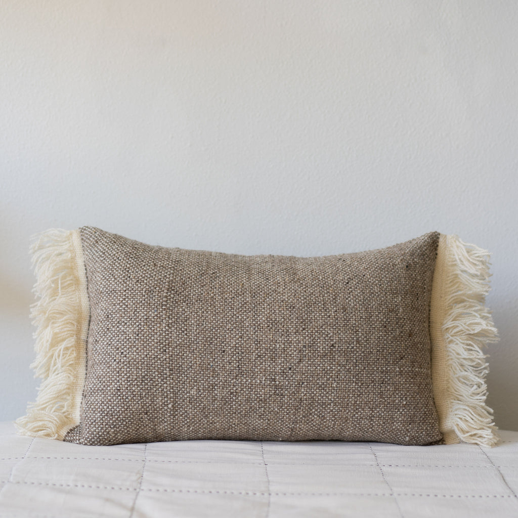 Tan and cream wool tweed lumbar pillow with cream fringed edges.