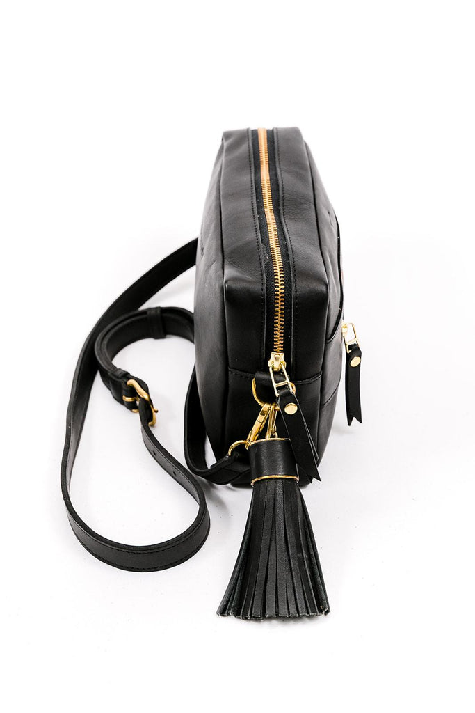 Black Leather rectangular purse with leather strap and big black leather tassel. Side view.