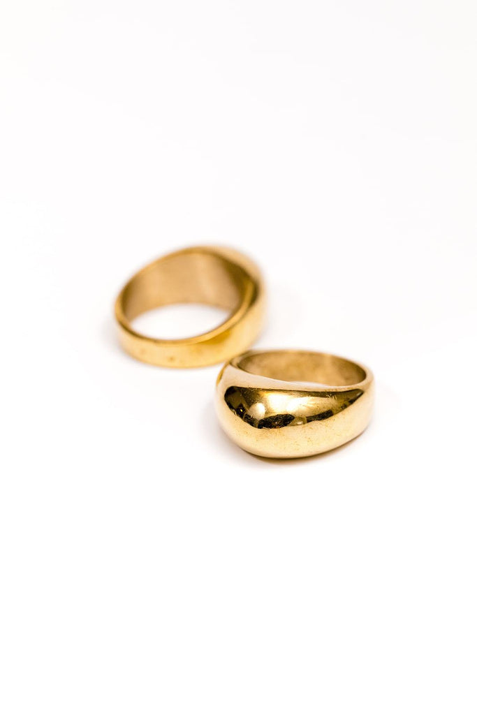 Two smooth chunky brass rings laying by each other, one facing away.