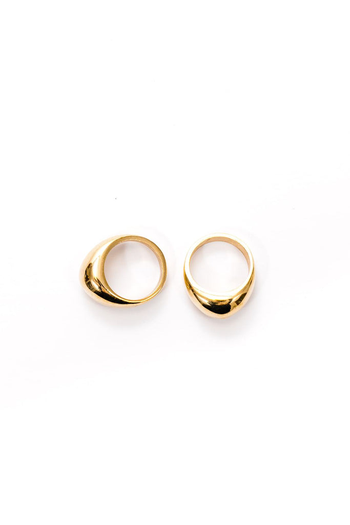 Two smooth chunky brass rings laying next to each other, one facing to the side.