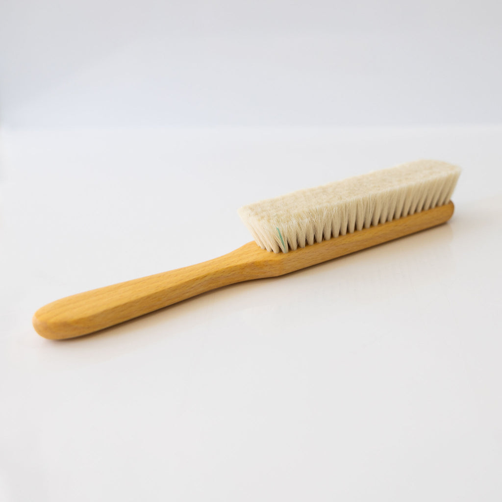 A slim dust brush made from goat hair and beechwood.