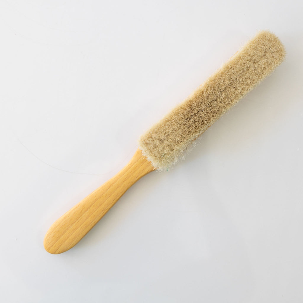 A slim dust brush made from goat hair and beechwood.
