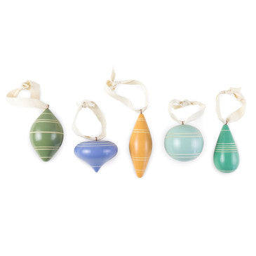 Group of five cool toned carved wood tree ornaments. Various rounded shapes.