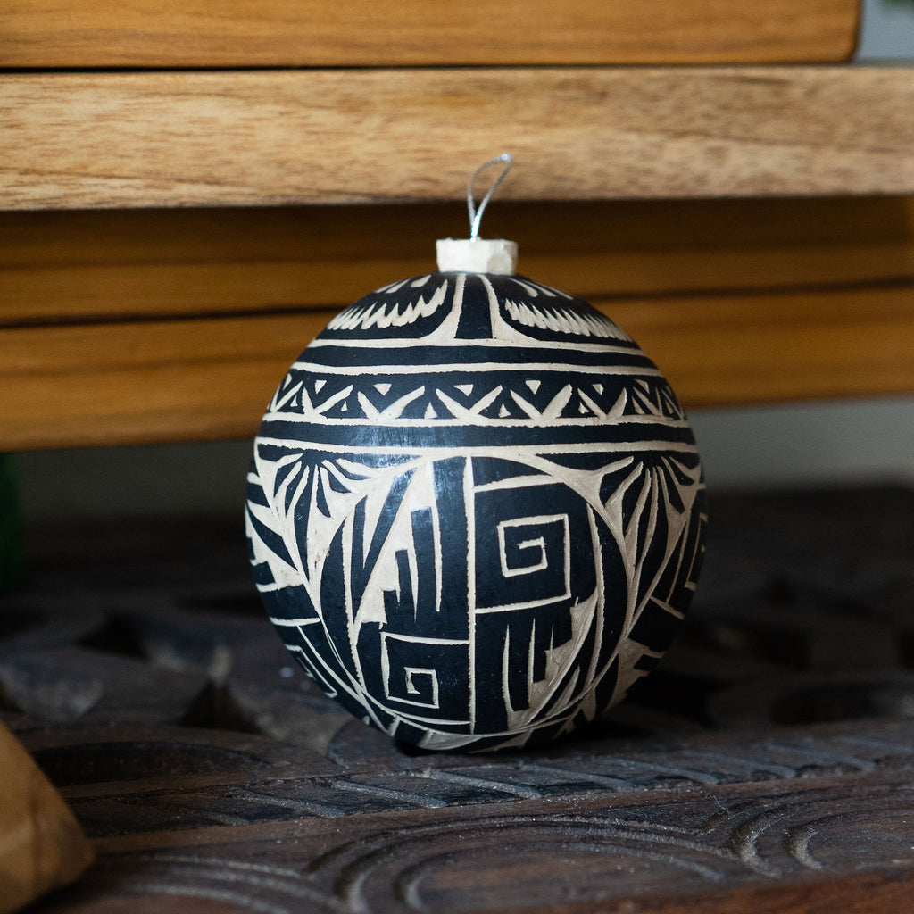Natural and black gourd tree ornament that is expertly carved in traditional Mexican flor and fauna and geometric motifs on varied wood background.