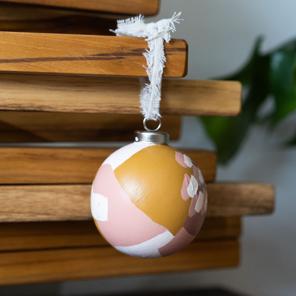 Handpainted abstract warm toned tree ornament hanging from a rustic ribbon.