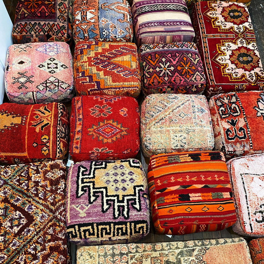 Picture of bright + colorful poufs / ottomans made from vintage Moroccan rugs when they can no longer be patched up as rugs! They are intricately designed and add such texture to a space.