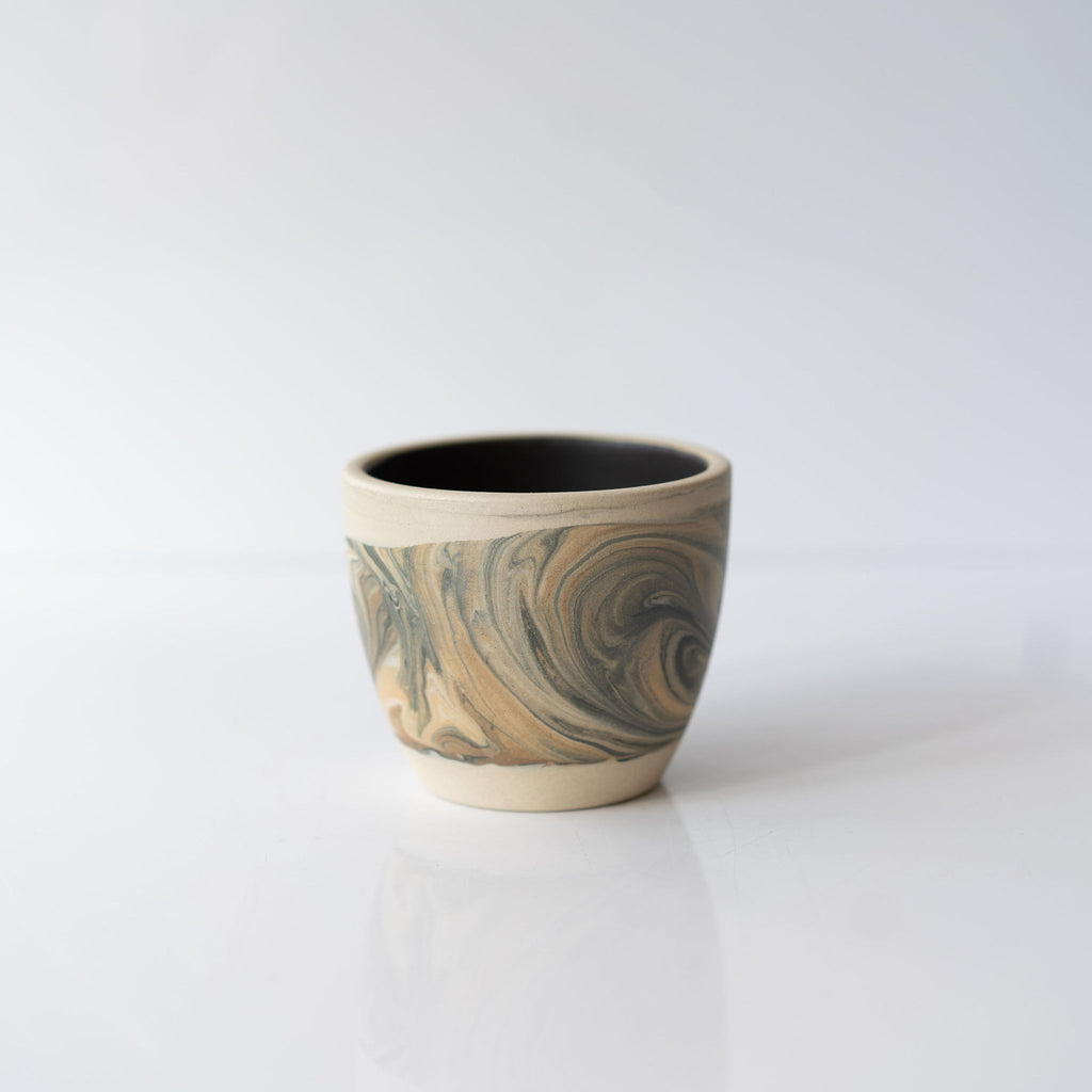 One black and tan marbled ceramic cup with a solid black interior.