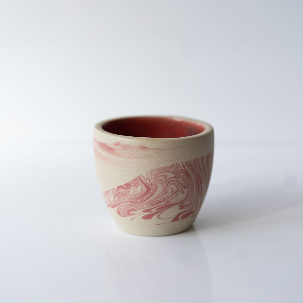 One pink marbled ceramic cup with a solid pink interior.