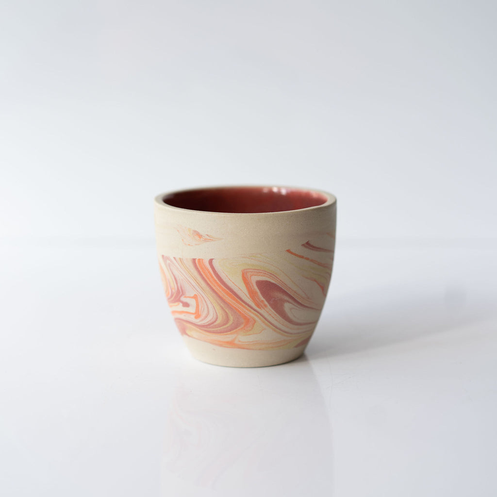 One pink and orange marbled ceramic cup with a solid pink interior.