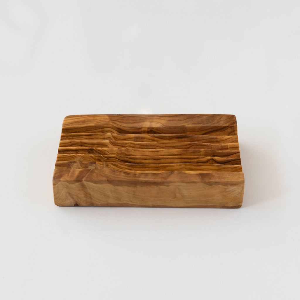 Rectangle olive wood soap holder with carved draining stripes against a light gray background.