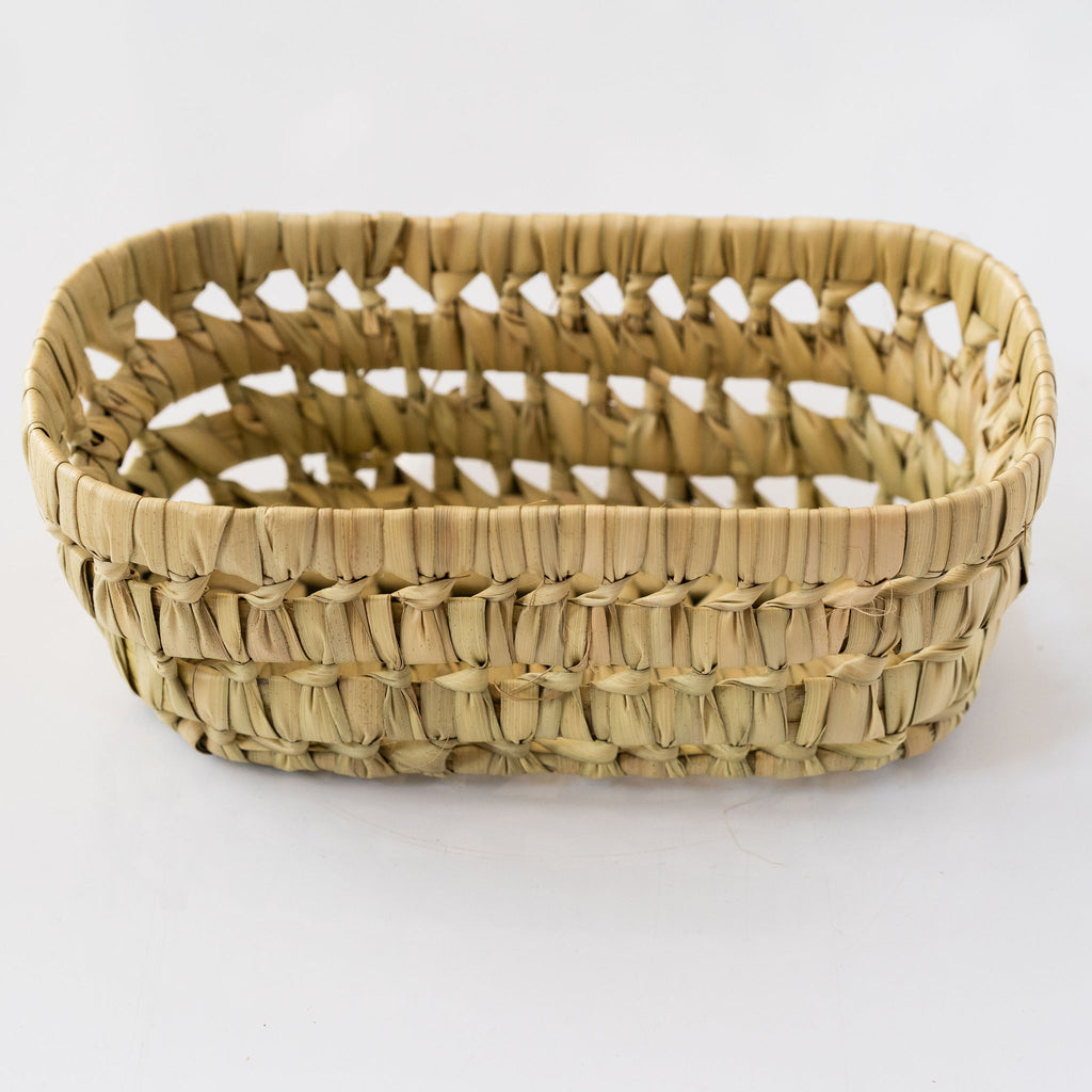 Palm fiber loosely woven rigid basket sits against a white background.