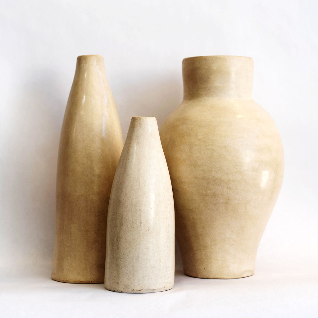 Group of three different sized and shaped creamy ivory Tadelakt vases. White background.