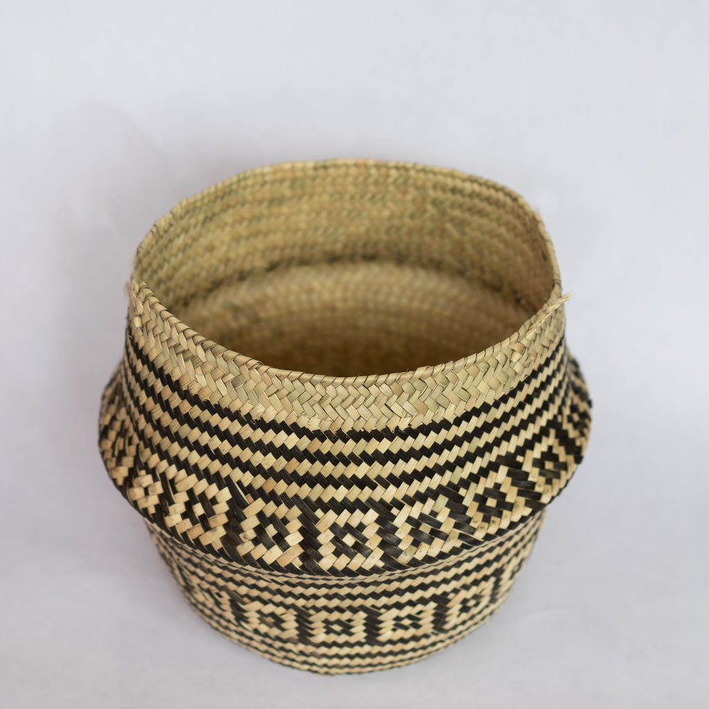 Handwoven palm fiber belly basket in traditional Oaxacan designs. Tan and black stripes alternate with rows of contrasting layered squares. Interior is natural tan. Gray background. 