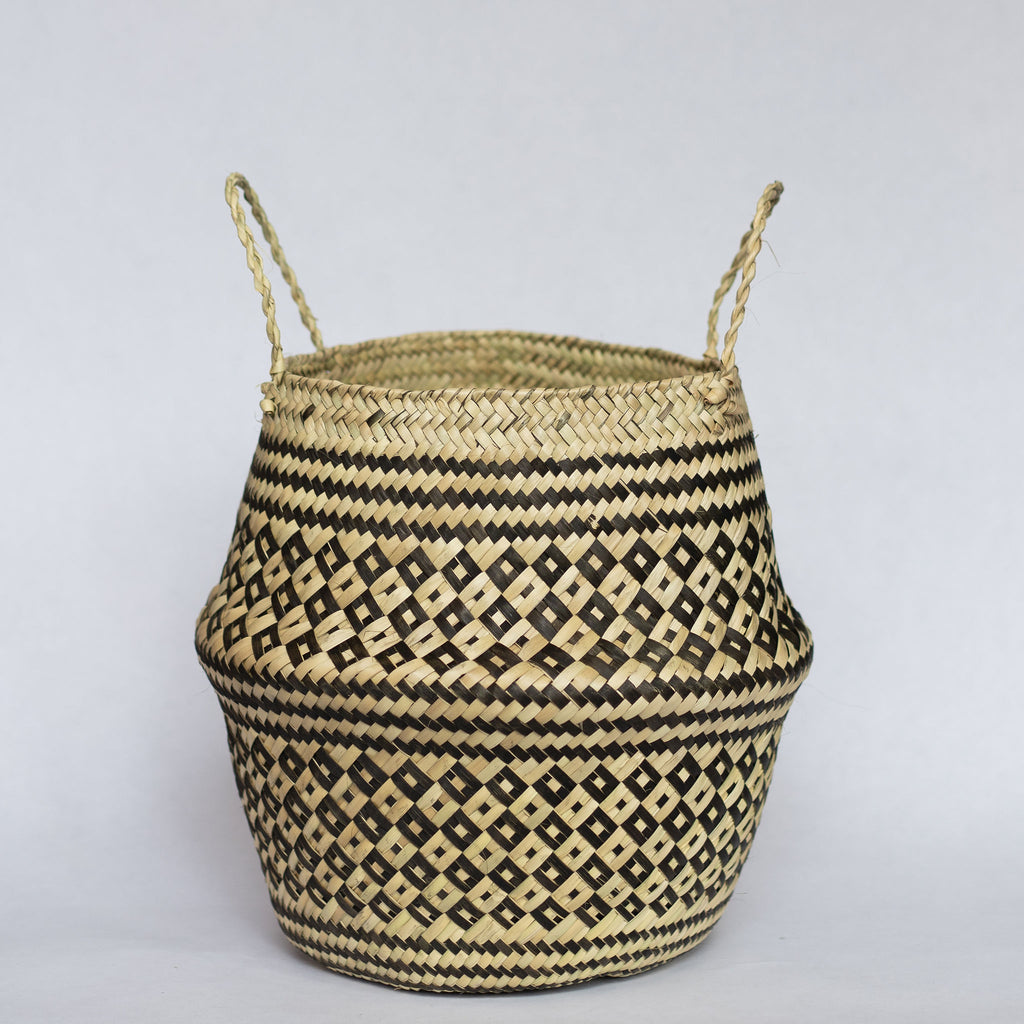 Handwoven palm fiber belly basket with handles in traditional Oaxacan designs. Tan and black alternating small diamonds with contrasting dots inside each diamond. Three black stripes at the middle and at the top and bottom edge. Gray background. 