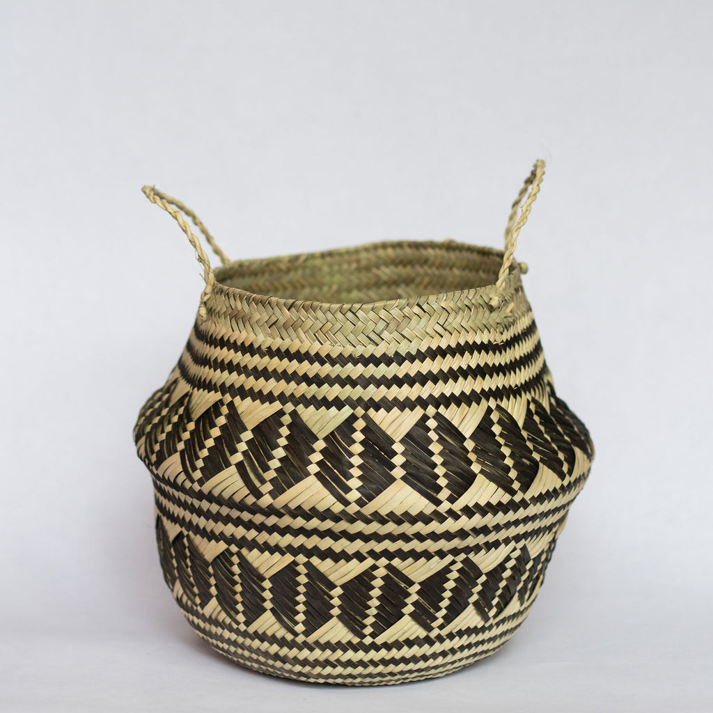 Handwoven palm fiber belly basket with handles in traditional Oaxacan designs. Tan and black horizontal stripes alternate with rows of graphic coffee beans. Horizontal stripes run along both top and bottom edge. Gray background.