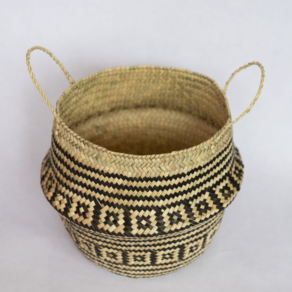 Handwoven palm fiber belly basket in traditional Oaxacan designs. Tan and black stripes alternate with rows of contrasting layered squares. Interior of basket is natural tan. Gray background.