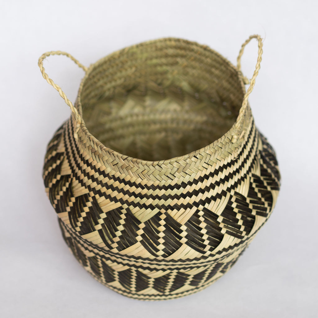 Handwoven palm fiber belly basket with handles in traditional Oaxacan designs. Tan and black horizontal stripes alternate with rows of graphic coffee beans. Horizontal stripes run along both top and bottom edge. Interior is natural tan. Gray background.