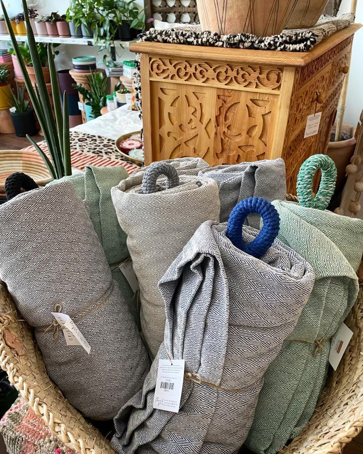 Gray, Black, Blue, and Green Hand-woven and Recycled Hammocks rolled up in a large handmade basket